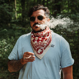 Rider wearing the red and white Rottweiler Motors bandana in a forest setting.