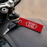 RTWR MTRS Full Send key tag attached to a motorcycle key on a seat