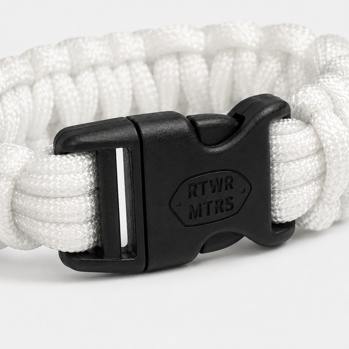 Close-up of the laser-engraved RTWR MTRS buckle on the 300 LB paracord bracelet